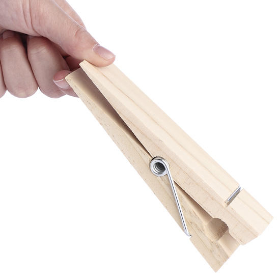 A hand holding a large wooden clothespin